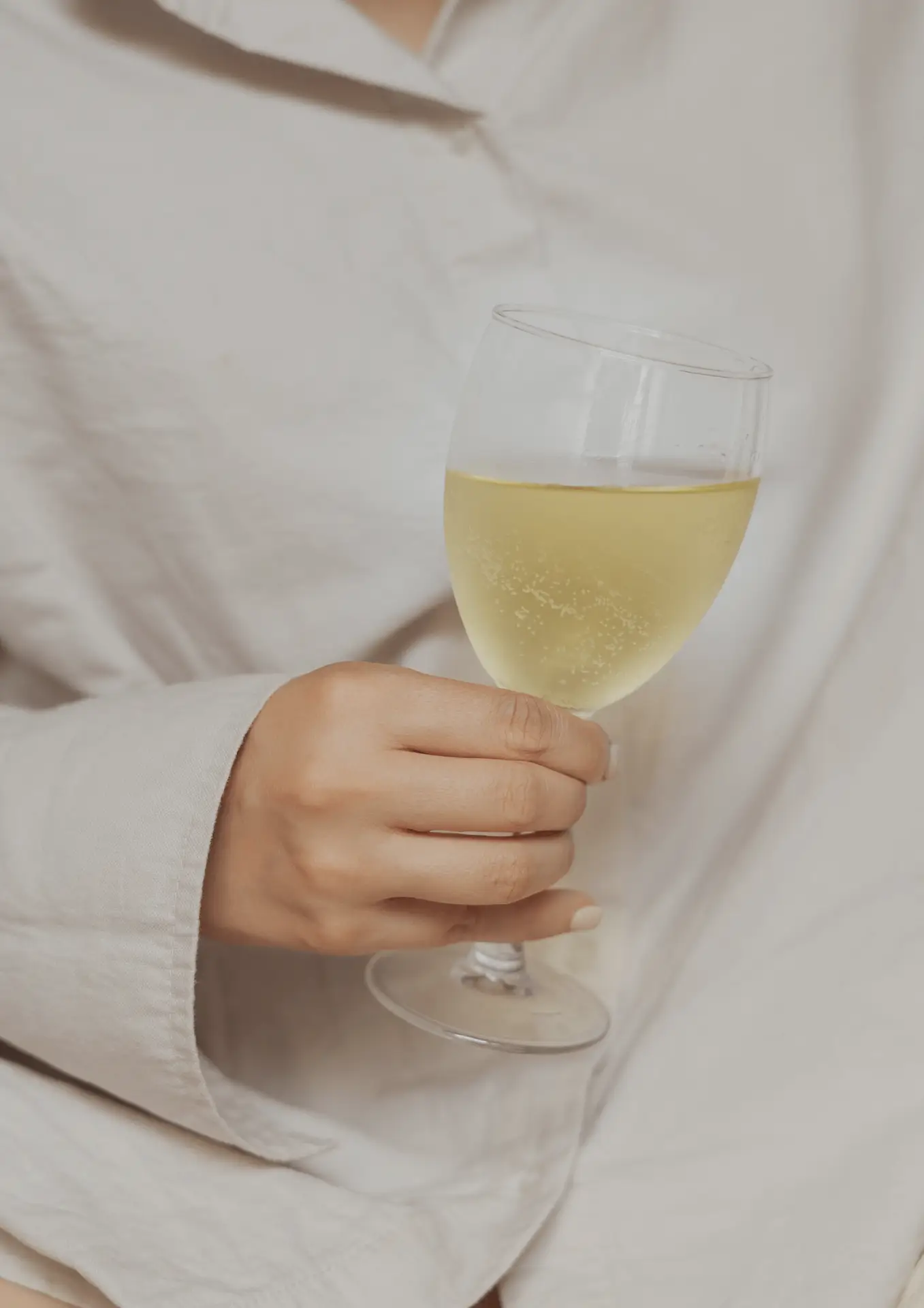 Vrouw met witte blouse die een glas champagne vasthoudt